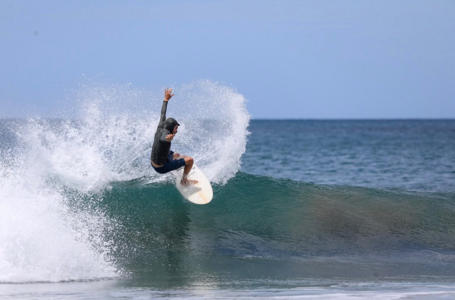 Surfista haciendo una maniobra y levantando agua en la cresta de la ola